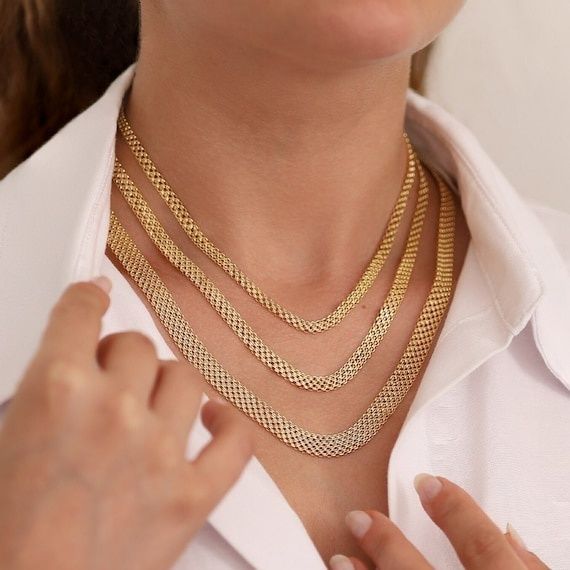 Närbild av person med flera guldfärgade Bismarckhalsband i olika längder